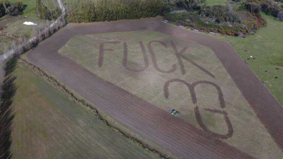 An aerial view of a field with the words "Fuck MG" have been ploughed into the land