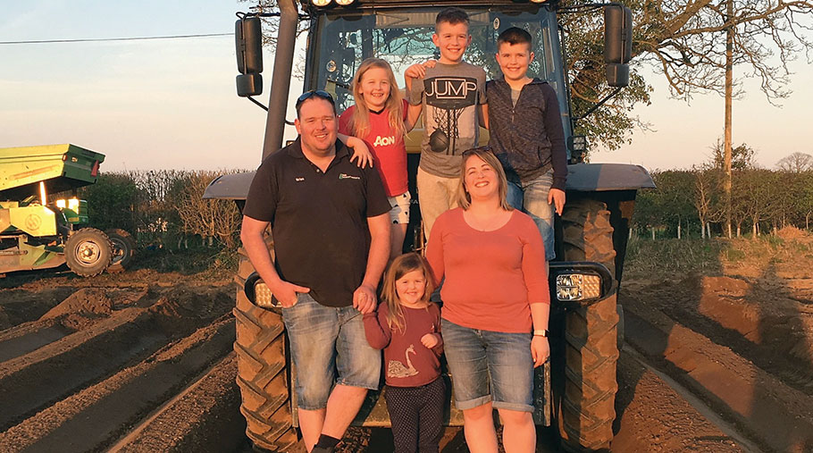 Brian and Carla-May Roberts are joined by four children as they stand in front of a tractor