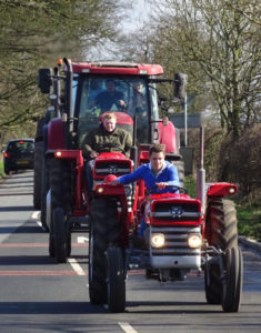 Two tractors without cabs lead a procession of tractors
