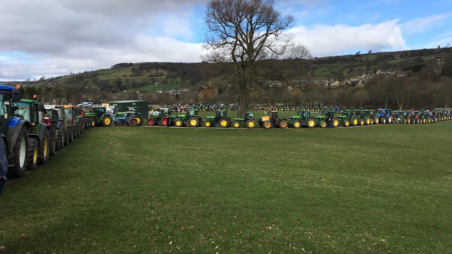 A procession of tractors travels through a field