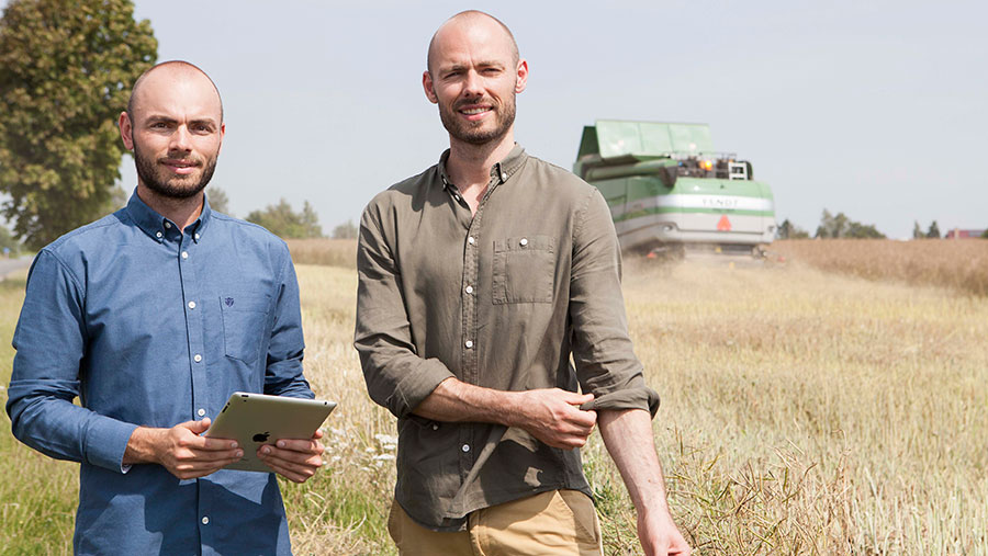 Anders and Søren Knudsen stand in front of a combine