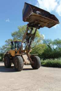 A Volvo loading shovel works in a yard