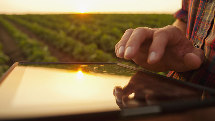 A close up of an ipad being held by farmer in a field