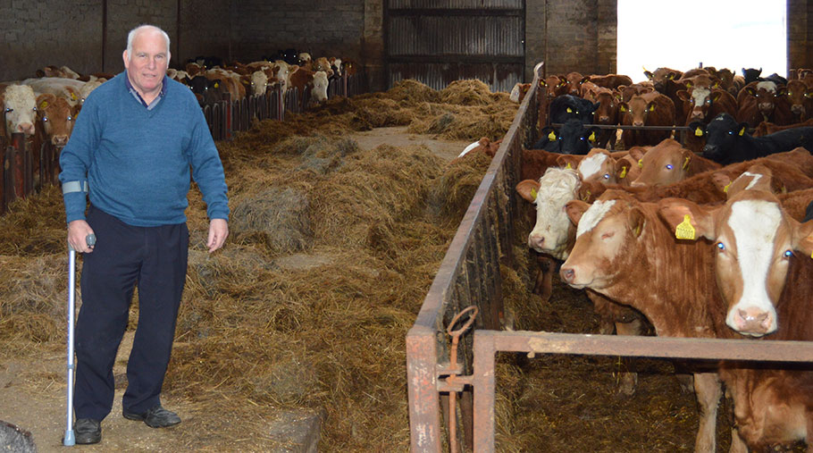 Ian Pirie stands in a livestock shed. He is using a crutch