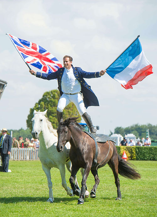 Lorenzo stands balanced on two moving horses carrying a Union flag in one hand and the Tricolour in the other