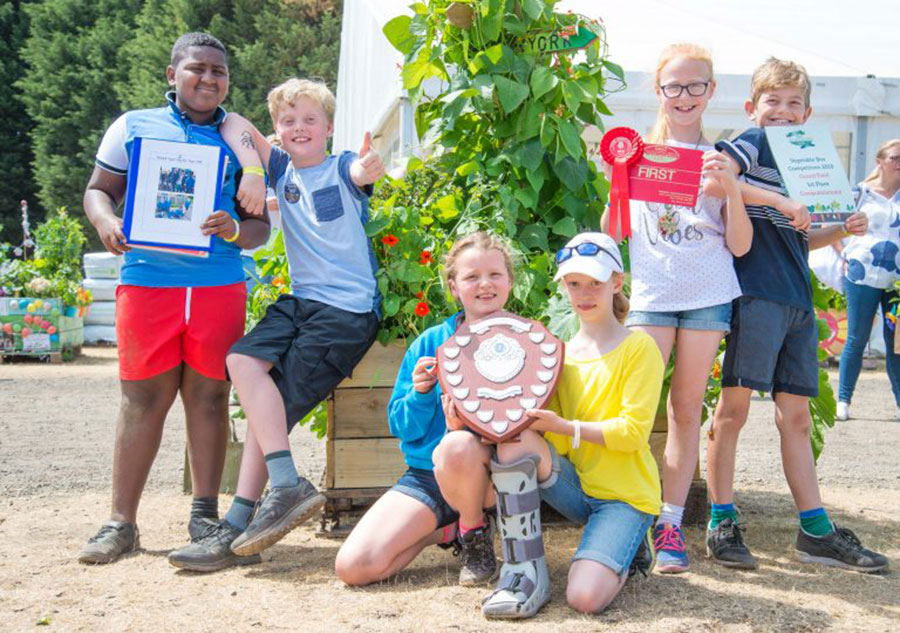 Six pupils pose for the camera holding a certificate and plaque for the Great Yorkshire Show's veg box challenge