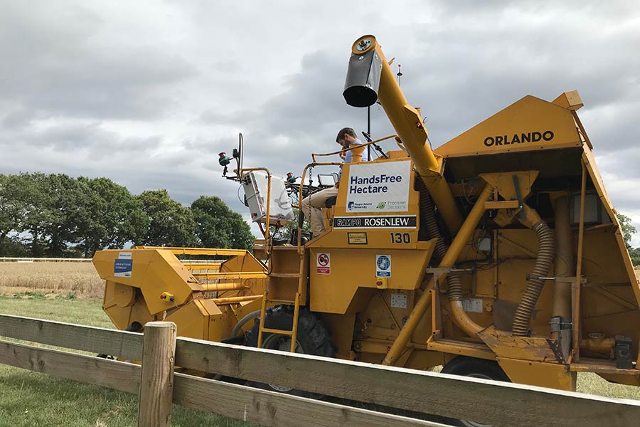 A man sits atop the Hands Free Hectare combine