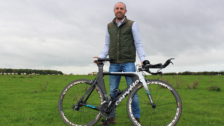 Adam Madge with his racing bike in a field of sheep