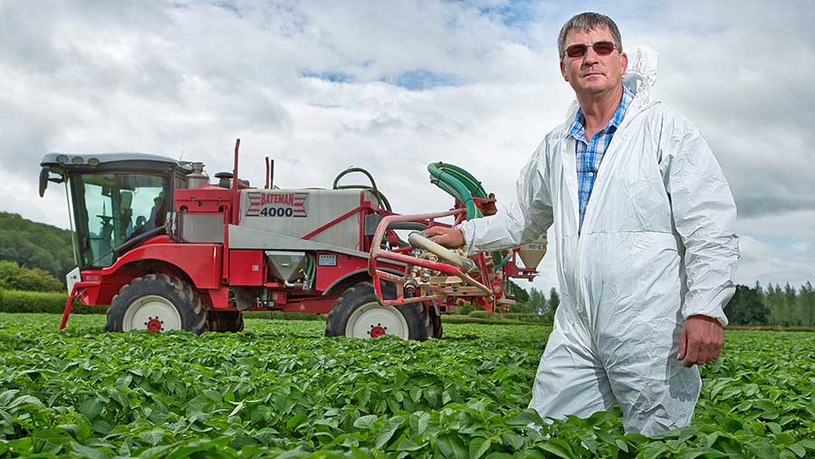 Richard Fox standing with a sprayer in a field