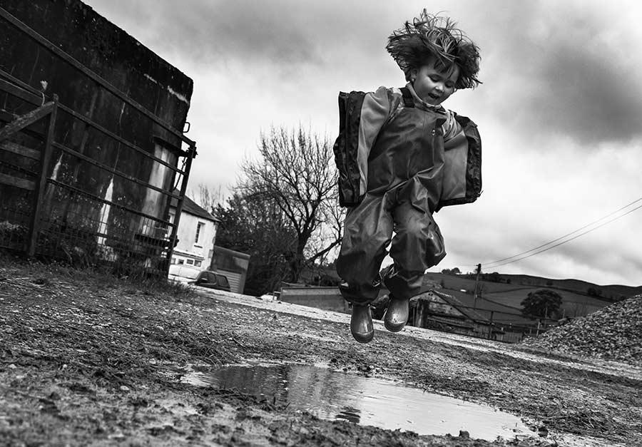 Black and white kid puddle jumping