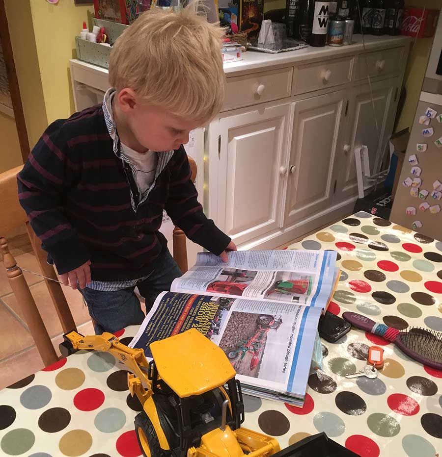 Boy reading farming magazine on kitchen table