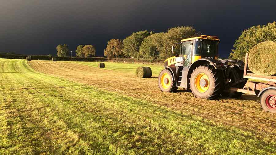 Tractor collecting bales in a field