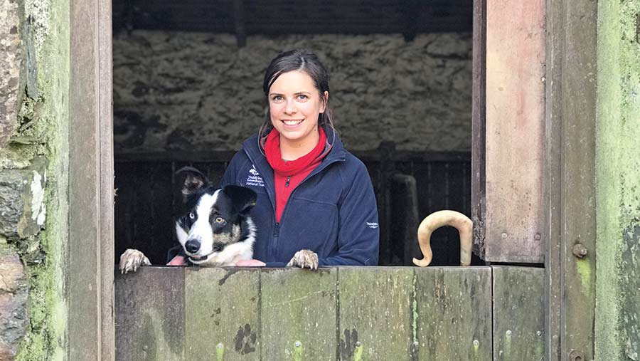 Teleri Fielden with her sheepdog peering out of stable door