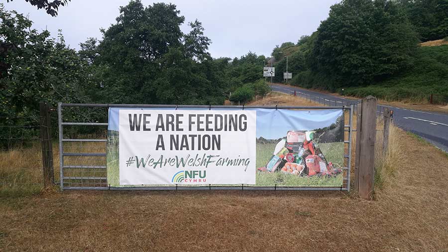 Poster on a farm gate reads: "We are feeding a nation. We are Welsh farming"