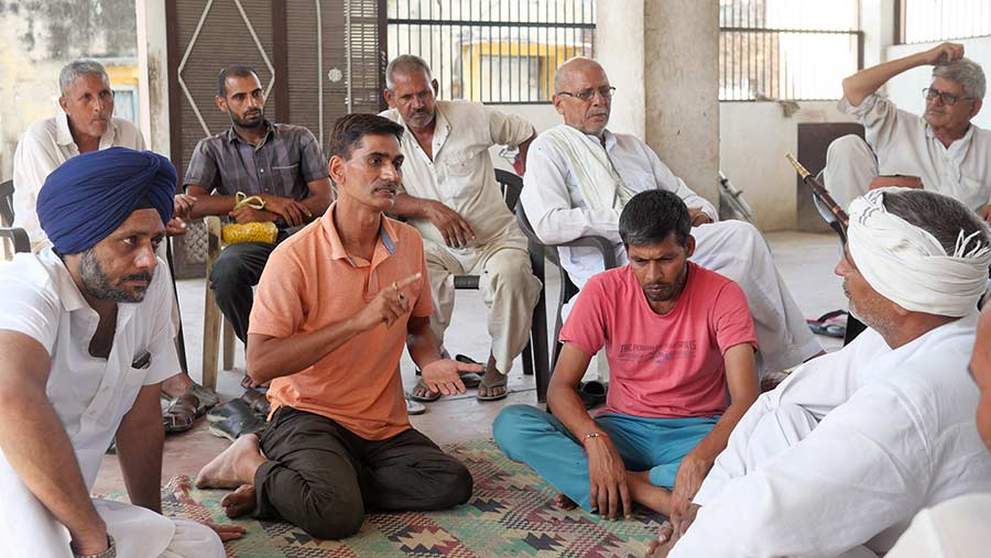 A group of Indian men sit on chairs and the floor conversing