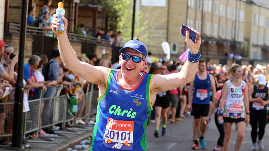 Chris Hewis raises his arms as he runs surrounded by other runners