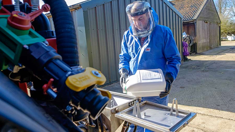 Farmer pours chemical into tank of crop sprayer