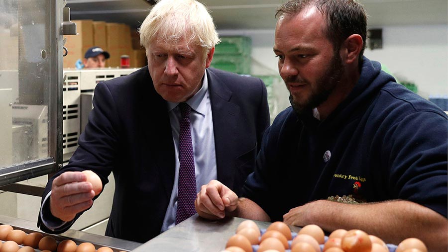 Boris Johnson inspects eggs with farmer Matt Shervington-Jones yesterday during his visit to Wales © Adrian Dennis/AP/Shutterstock