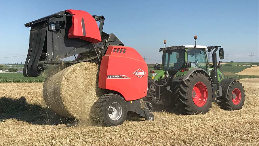 A tractor pulling and red baler