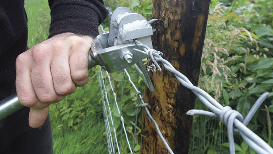 Close-up of staple puller working on a fence