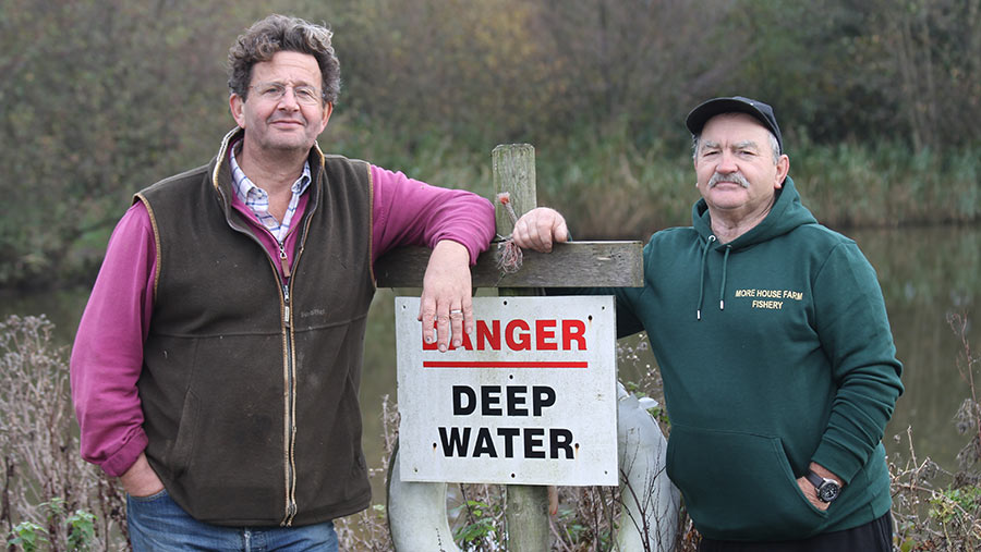 Two men by a lake with a sign that reads Danger, Deep Water