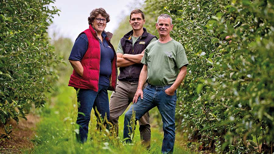 Esther, Henry and Monty Rudge standing in orchard