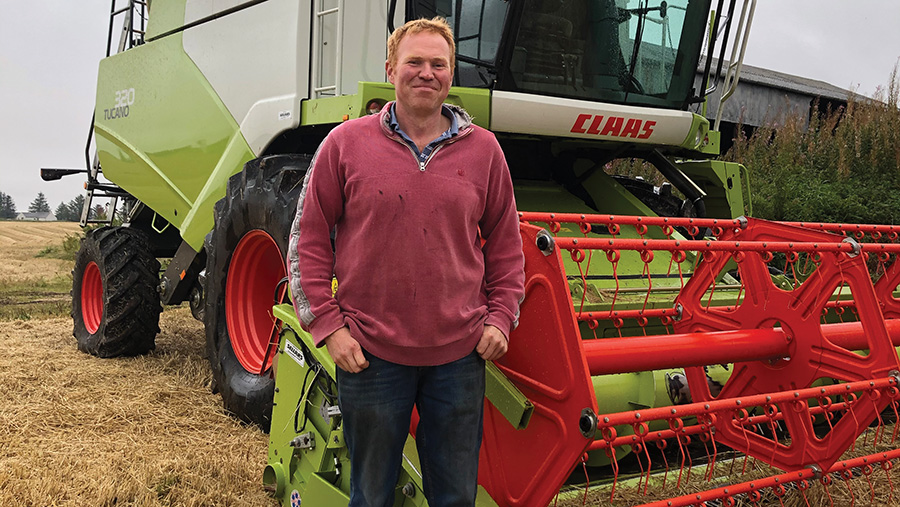 Peter Booth standing with his Claas Tucano combine
