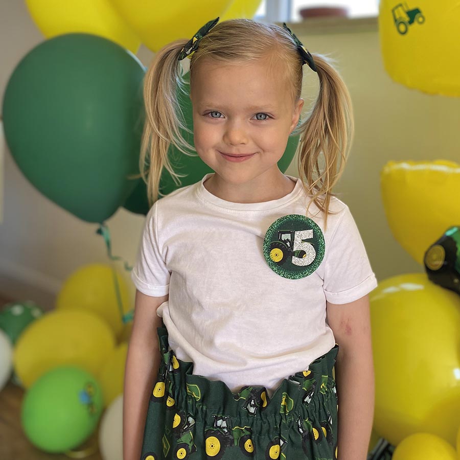 Girl with John Deere party balloons