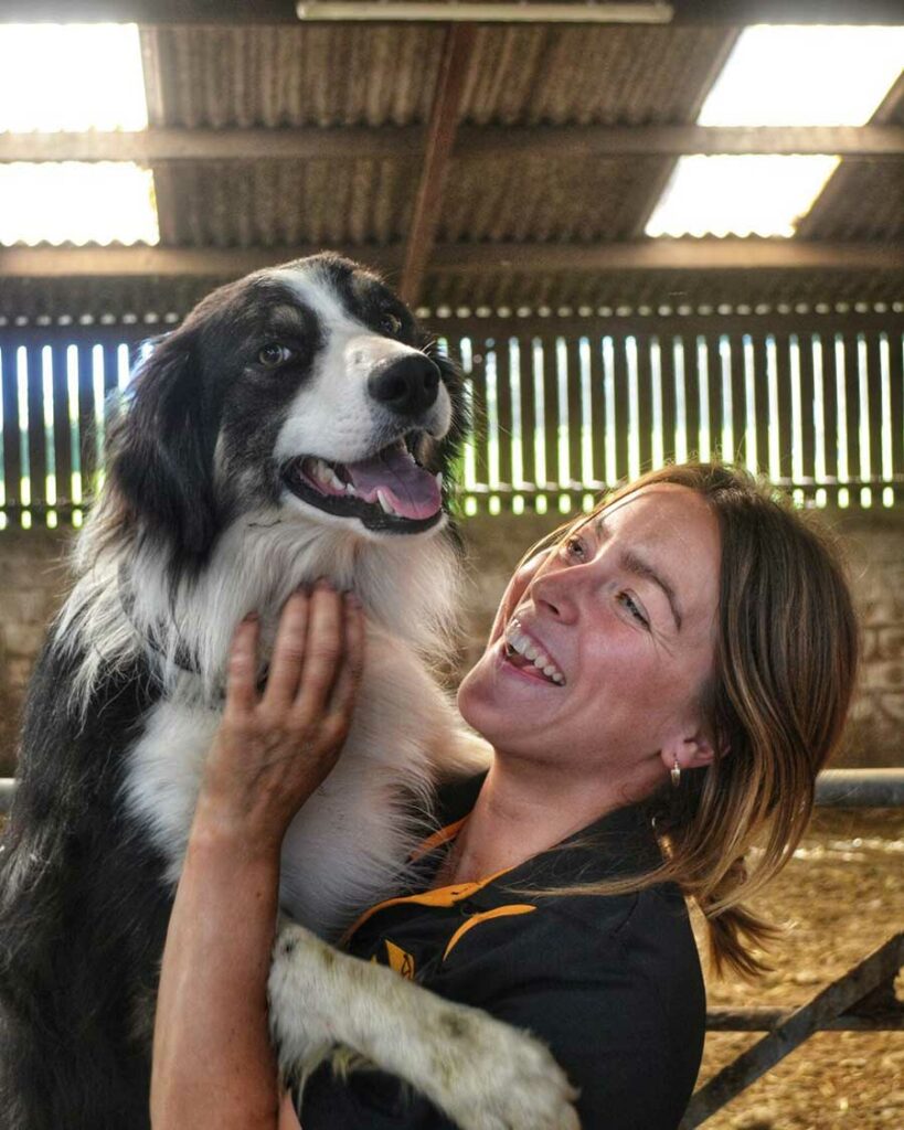 Dog cuddled by worker in shed