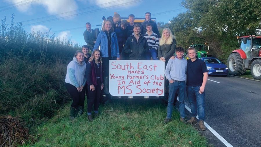 A group of people surround a hand-painted sign