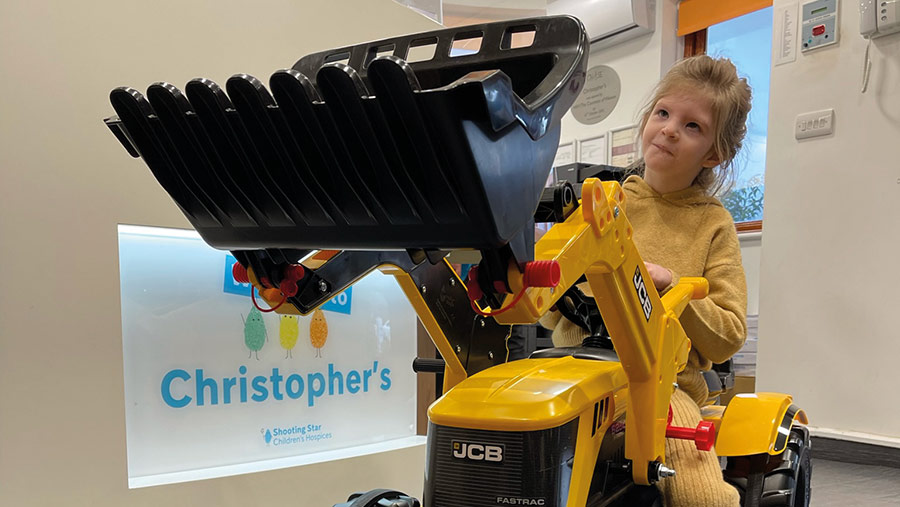 Child playing on toy tractor at Shooting Stars Children's Hospice