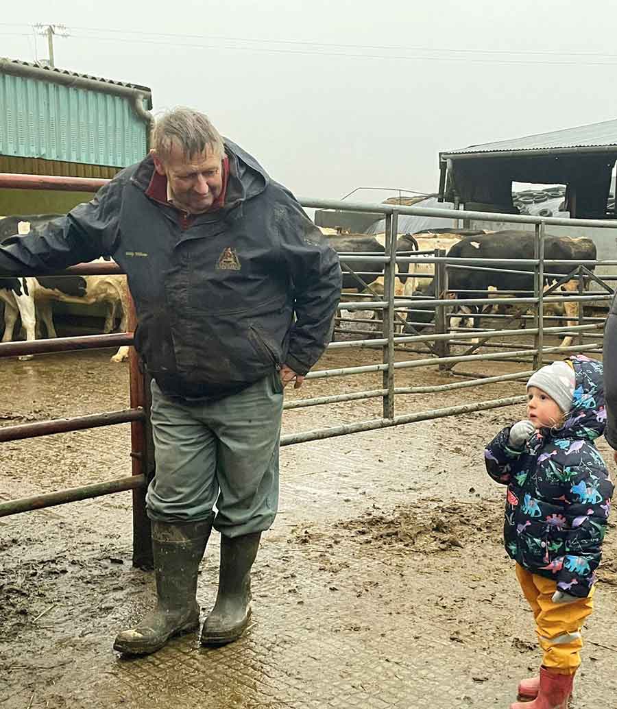 Man and child next to a pen of cattle