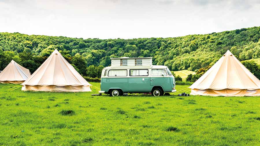 VW campervan in a field with yurts