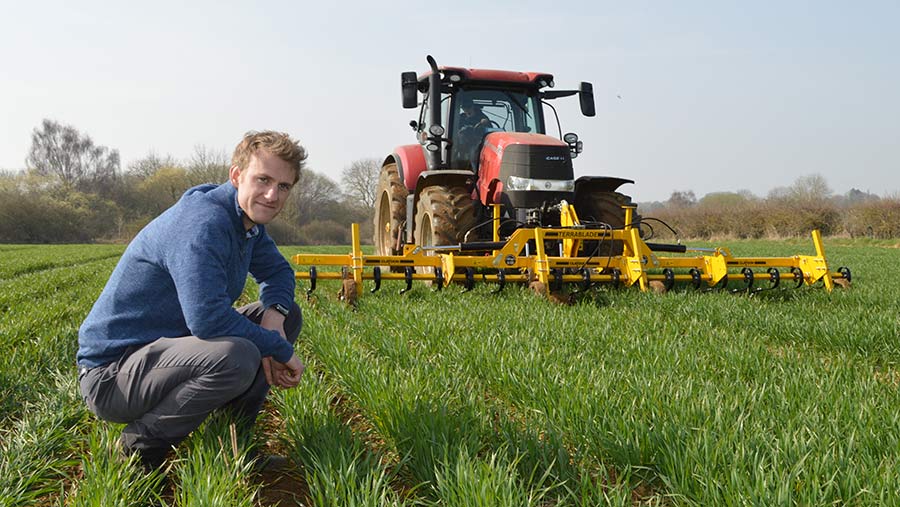 Man kneels in front of tractor and hoe