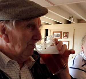 Man in a cloth cap drinking a pint 