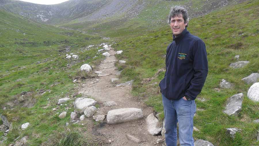 Man stands on a rough track on a hillside