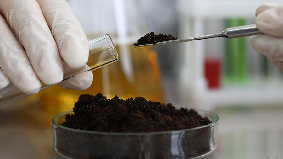 Female chemist in white protective gloves hold test tube against chemistry lab background closeup. Express research crop soil content of beneficial and harmful substances concept