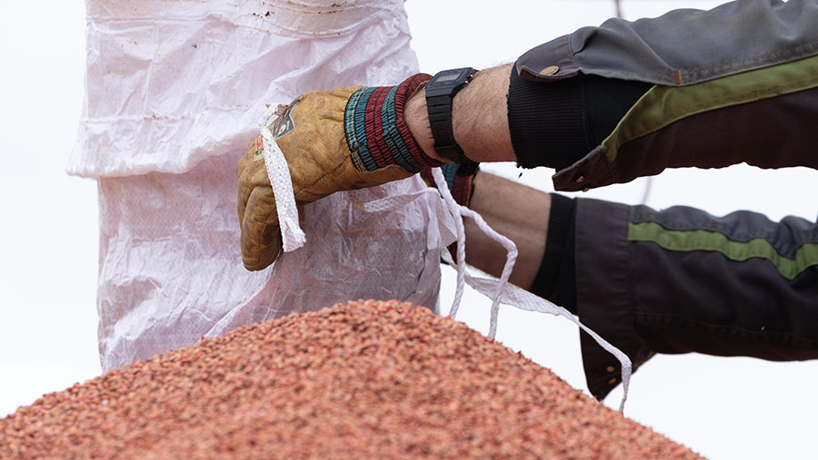 Hands opening a bag of seed to fill a drill hopper
