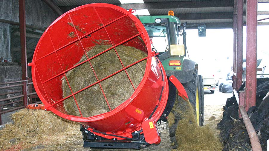 Round bale spreader in a cattle shed