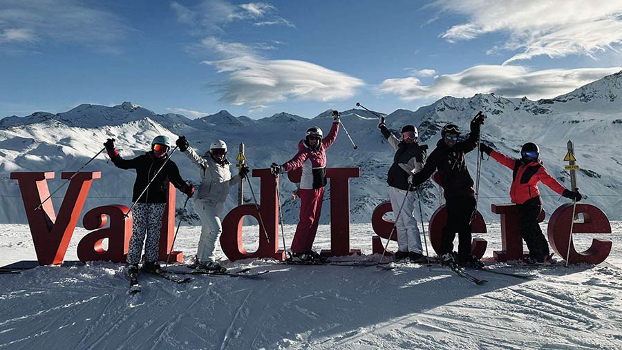 Skiers pose with a sign reading Val d'Isere