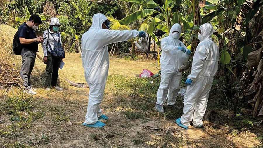 Men in biohazard suits disinfecting village in Cambodia