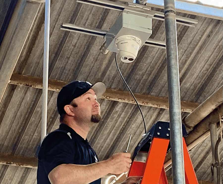 Man on a ladder near a roof-mounted camera