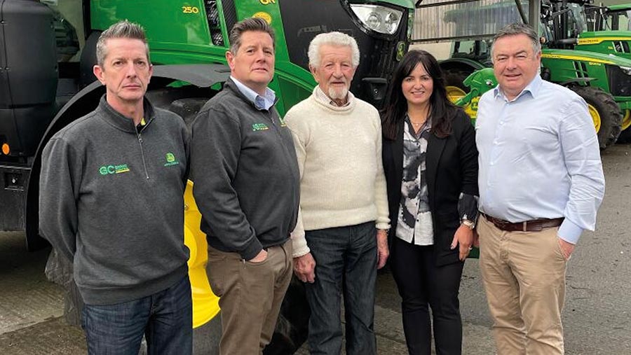 Group of people pose in front of a tractor