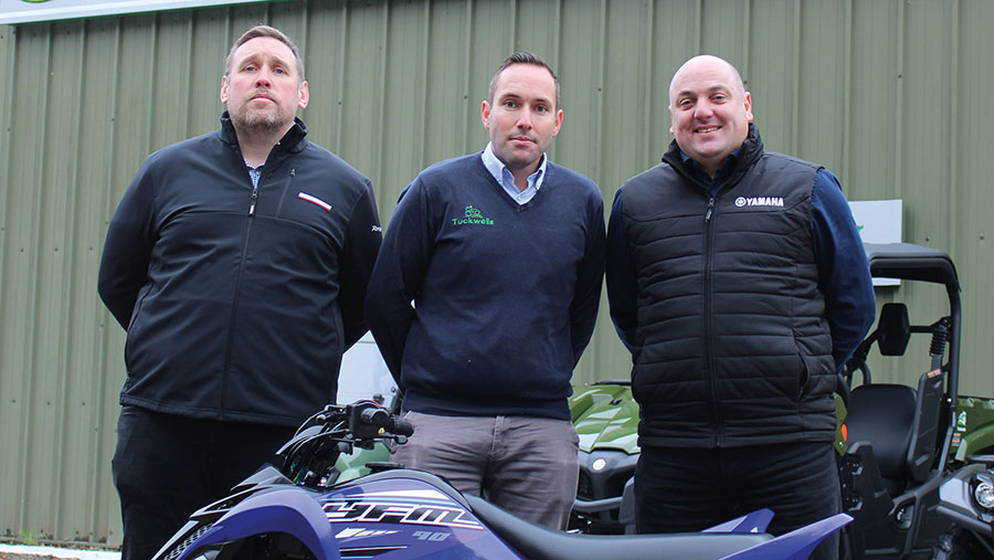 Three men pose with a quad bike