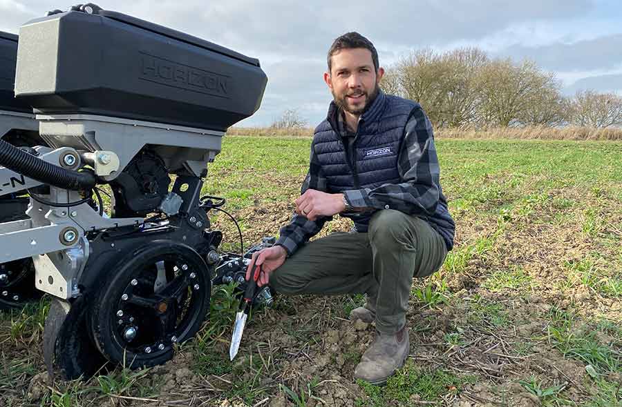 Man squatting beside a seed drill