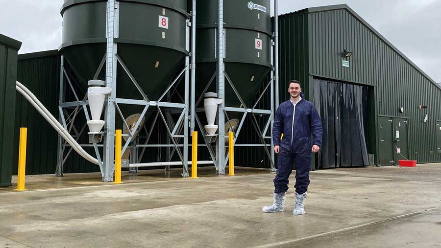 Man stands in a farmyard with feed silos