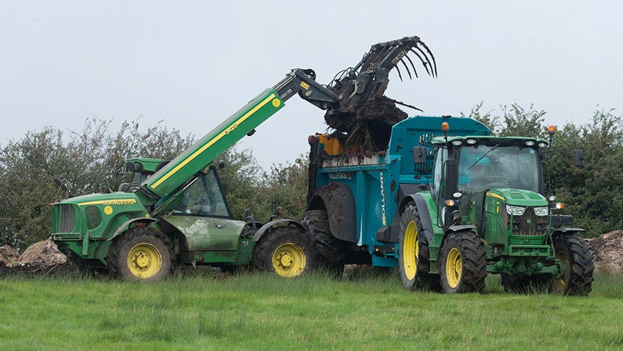 Loader adding solid muck to a trailer