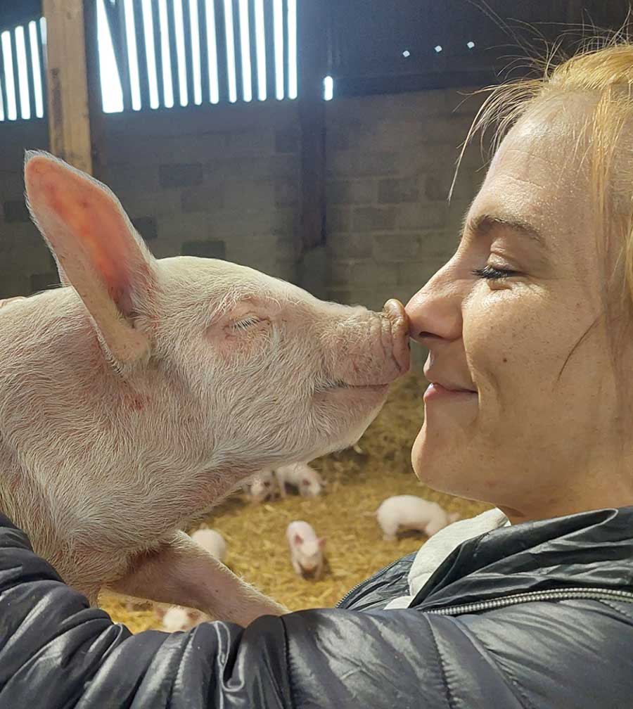 Young woman nose-to-nose with piglet