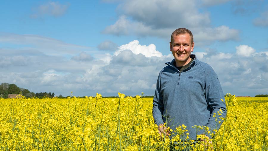 Male farmer stood in a field of flowering oilseed rape