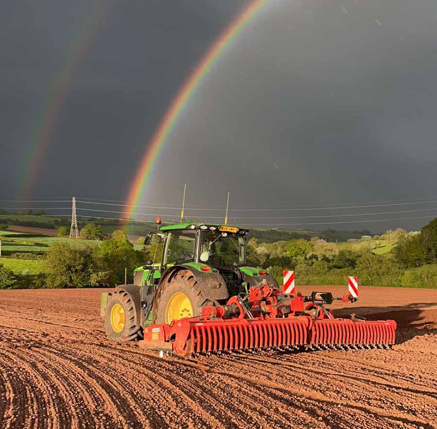Tractor in action with rainbow appearing on the horizon